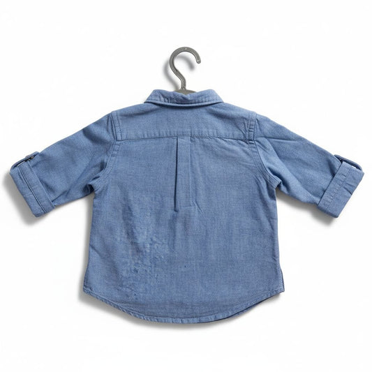 Blue denim shirt on a hanger against a white background