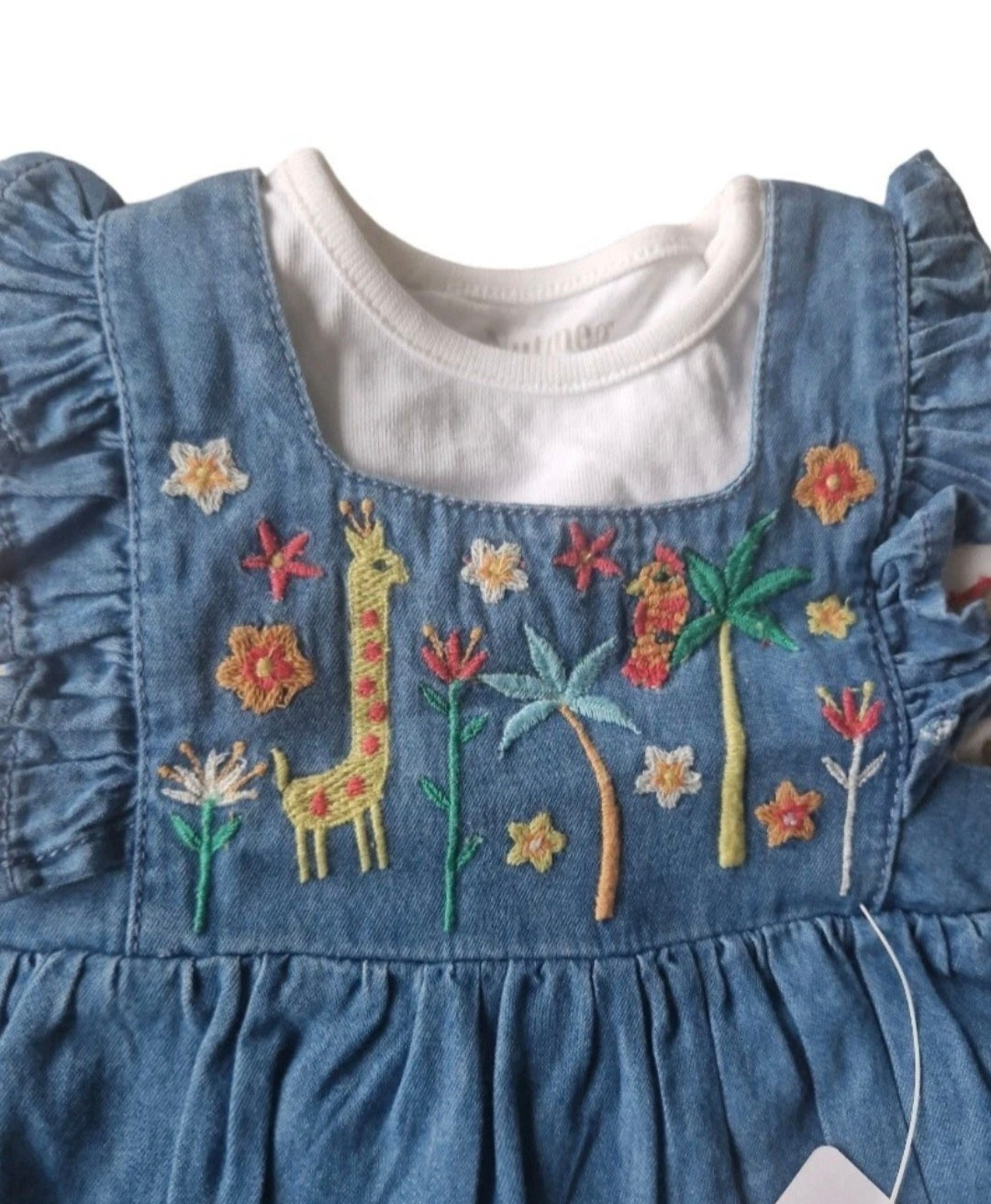 Children's denim dress with embroidered giraffe and floral design on a white background