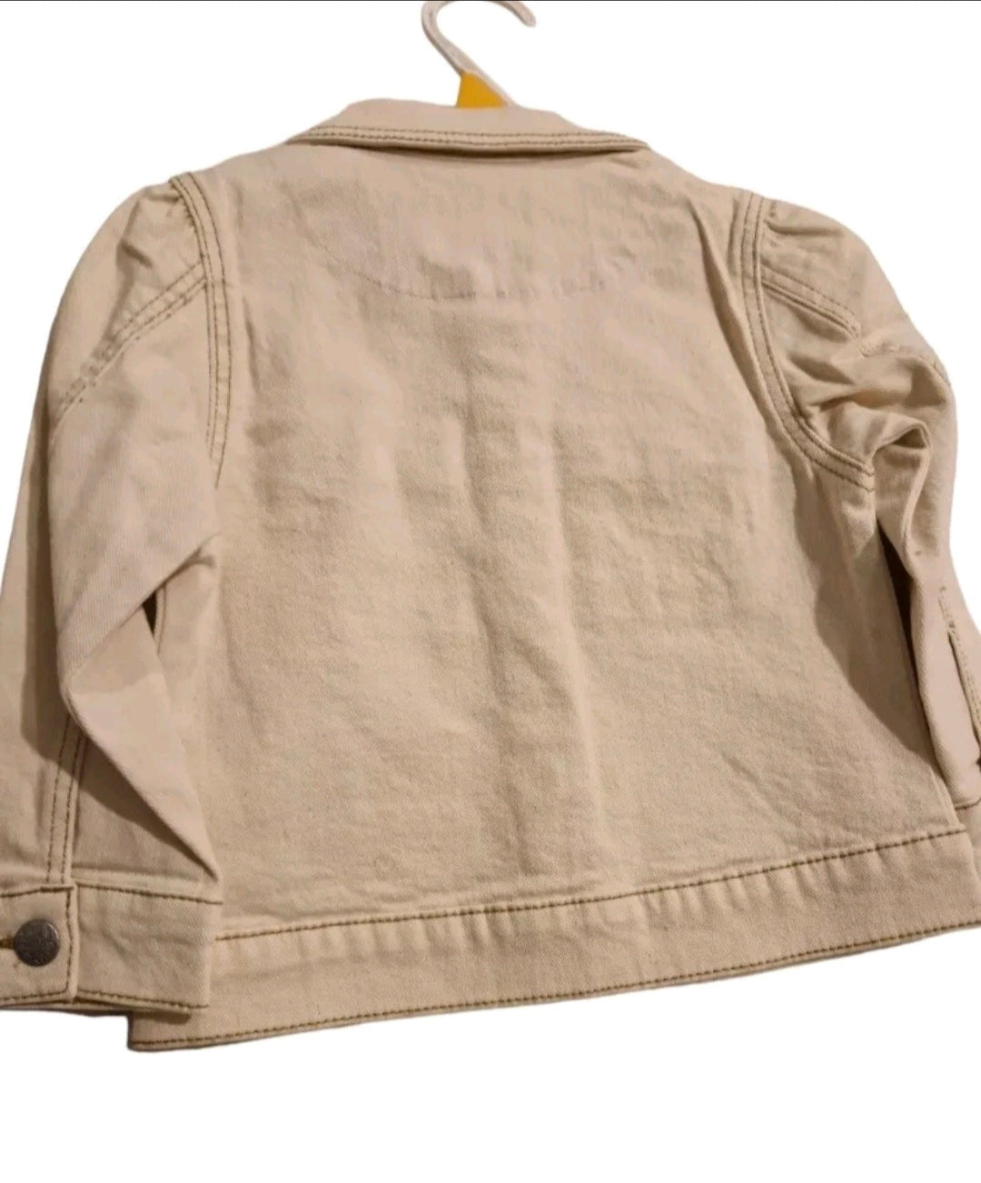 Beige jacket on a hanger against a white background