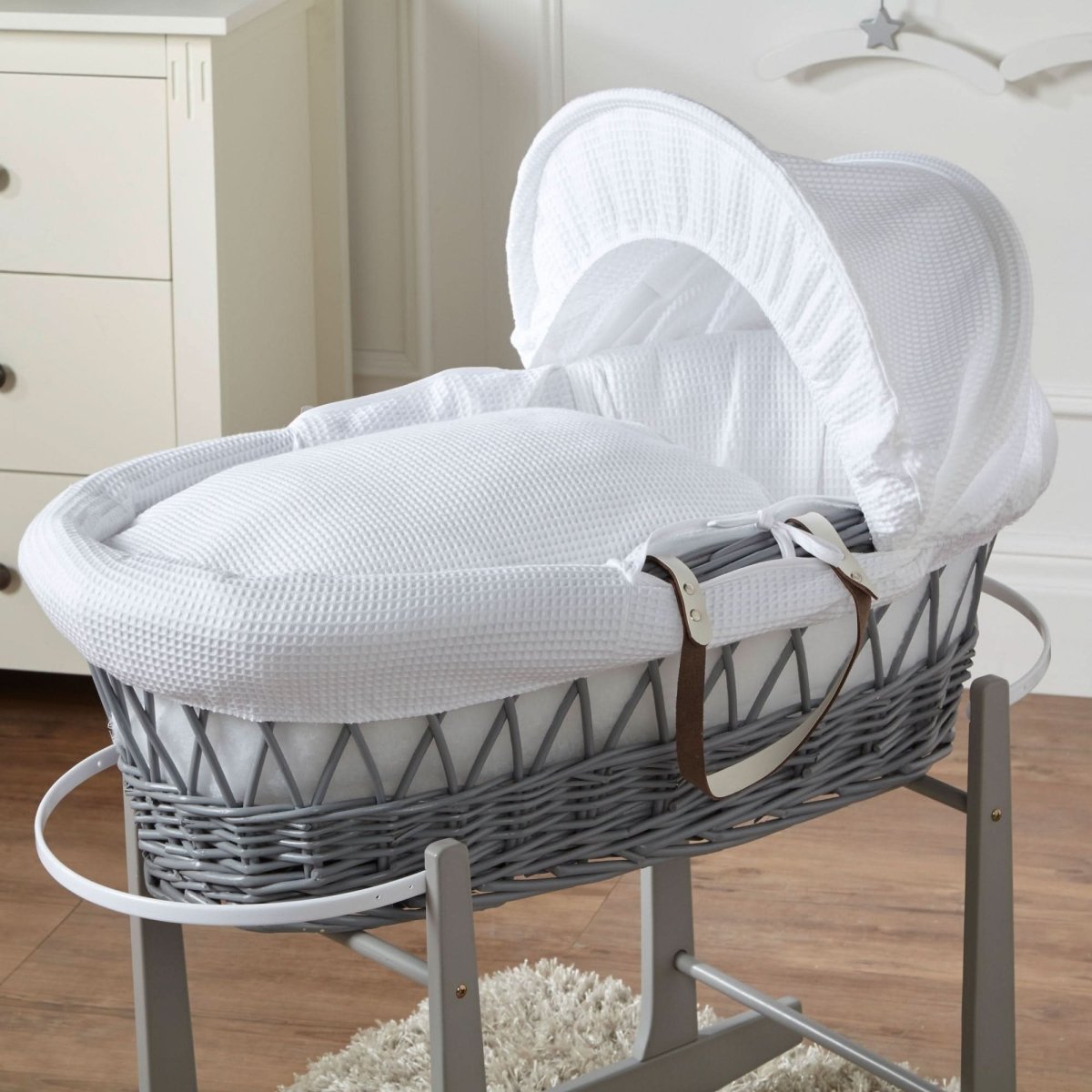 Gray wicker Moses basket with white bedding in a nursery setting
