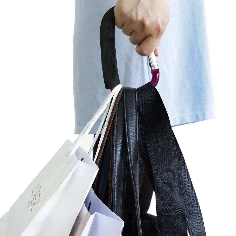 Person holding a black umbrella over a white shopping bag with a visible brand logo.