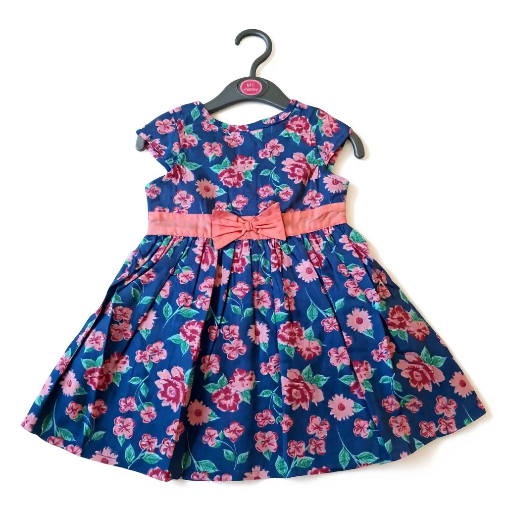 Floral dress with a pink bow on a hanger against a white background