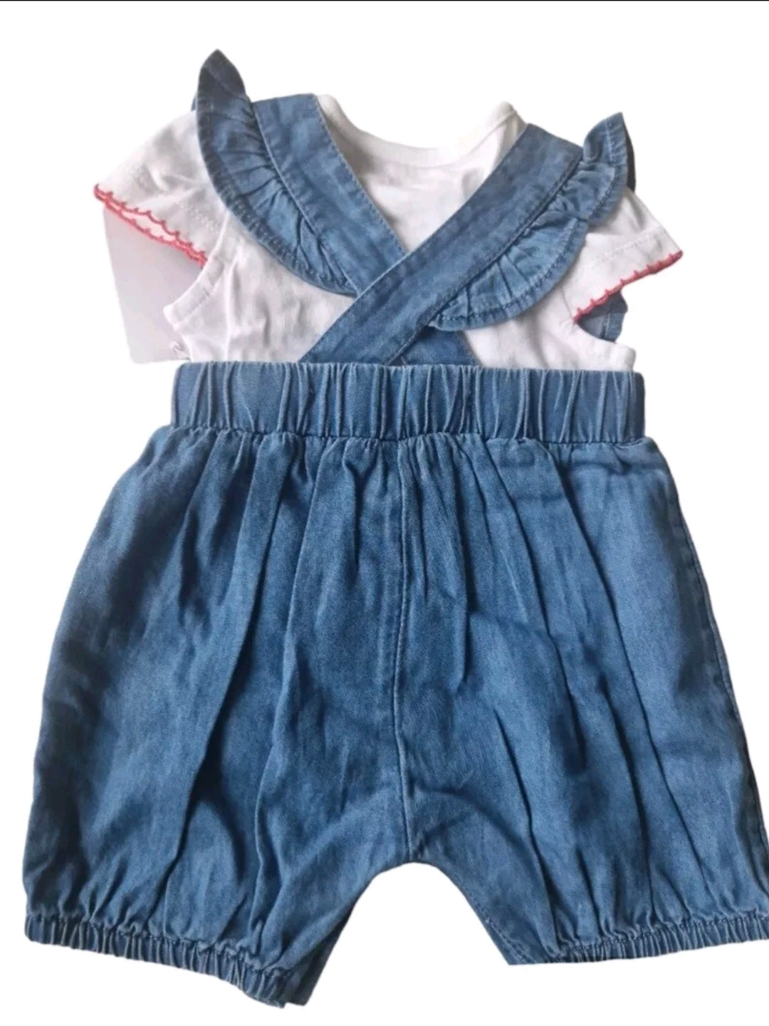 Children's outfit with denim overalls and ruffled top on a white background