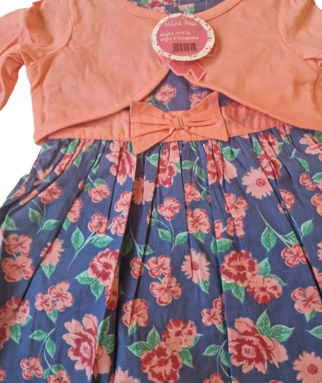 Children's dress with floral pattern and pink bow, worn over a matching top.
