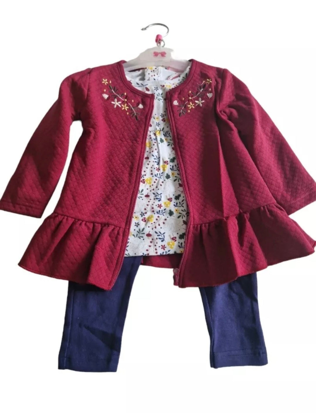 Children's outfit with red jacket, floral dress, and blue pants on a white background