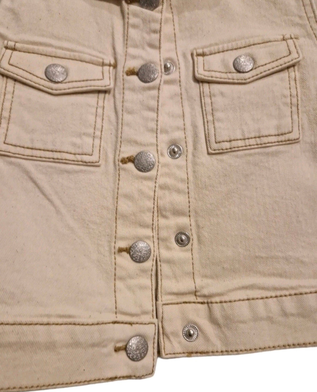 Close-up of a beige denim jacket with button details on a white background