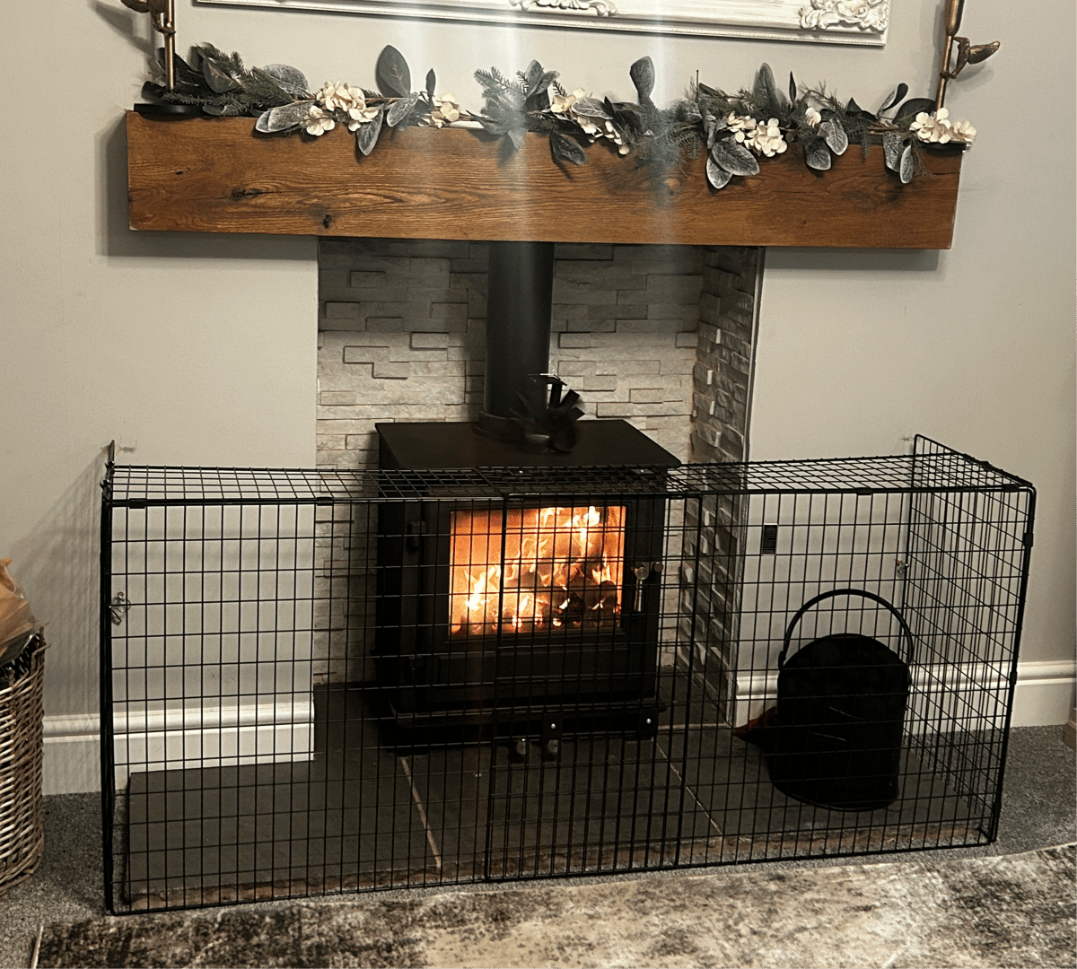 Wood-burning stove with decorative fireplace mantel and garland.
