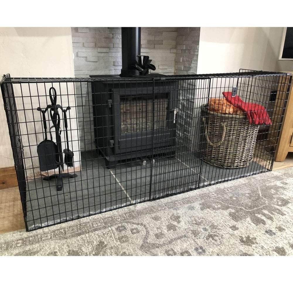 Black metal fireplace screen with tools and a basket in front of a stone fireplace.