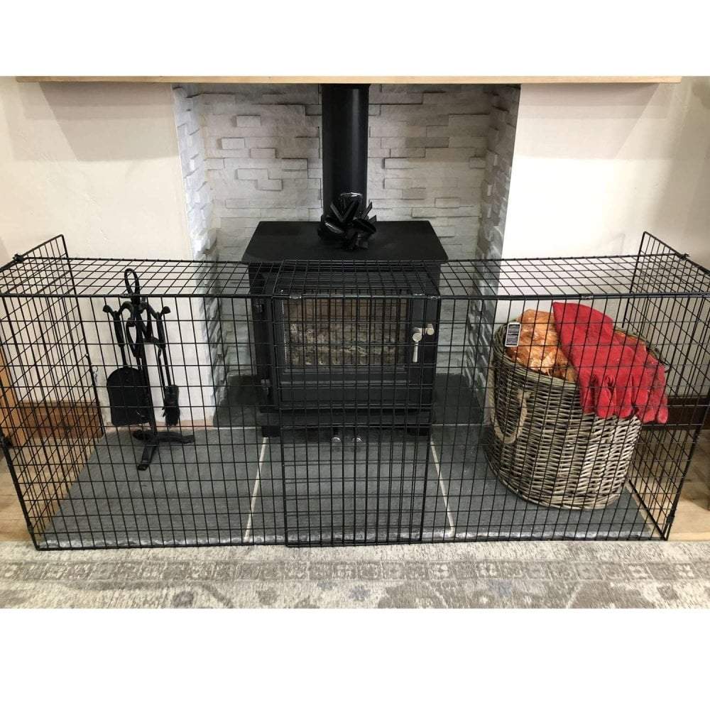 Black metal fireplace screen with a basket of wood and red blanket in front of a stone fireplace.