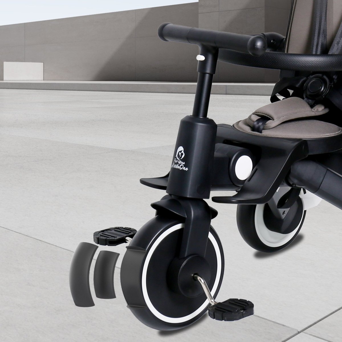 Black tricycle attachment on a stroller with a neutral background