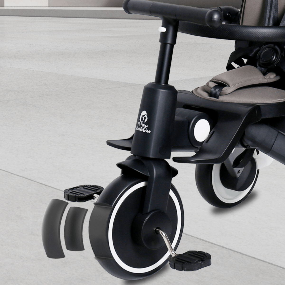 Close-up of a stroller wheel with a brand logo on a light gray floor.