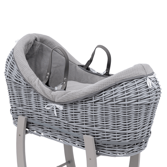 Gray wicker baby Moses basket with a textured cover on a white background
